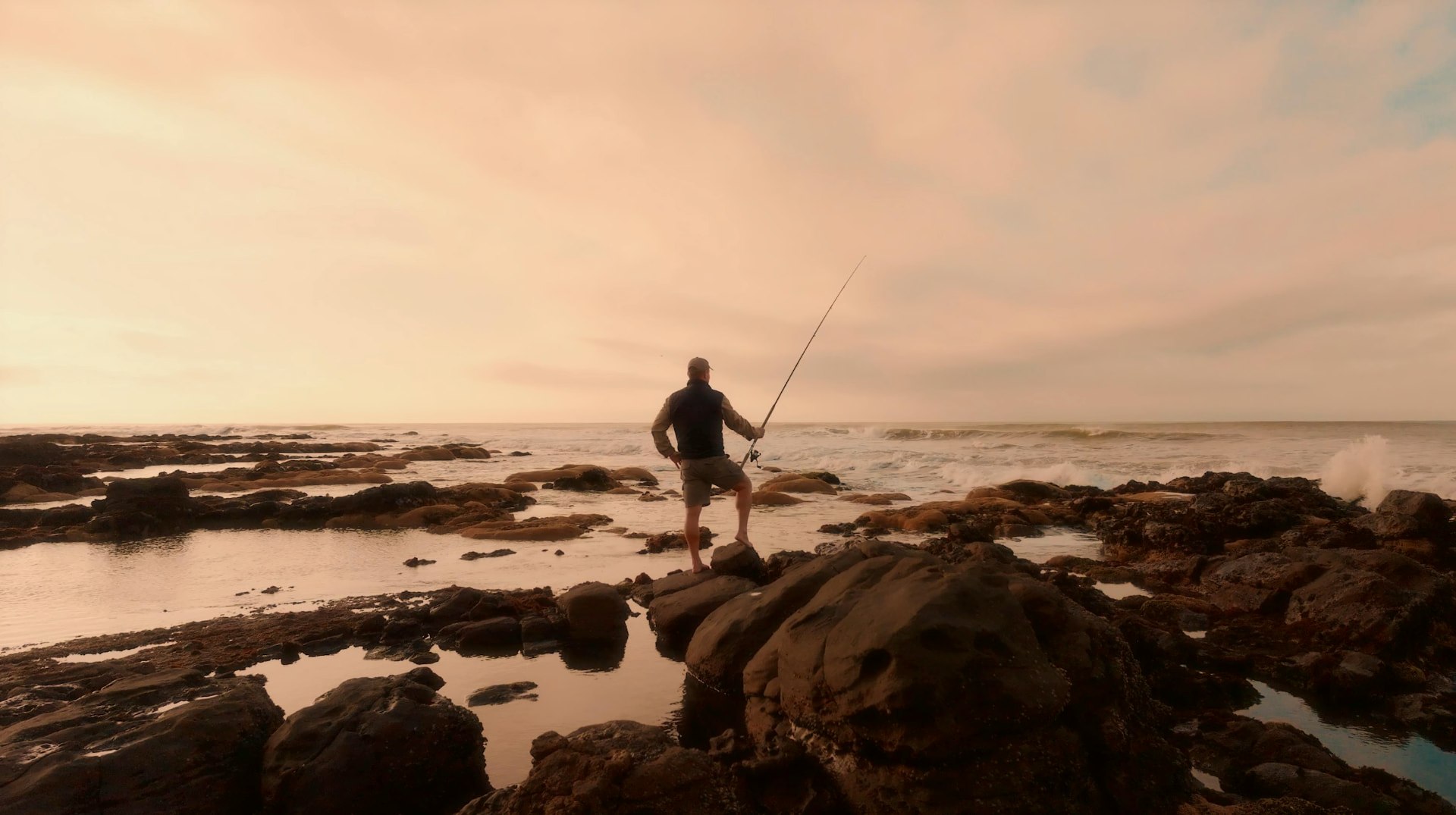 A guest rock fishing among tidal pools at dusk