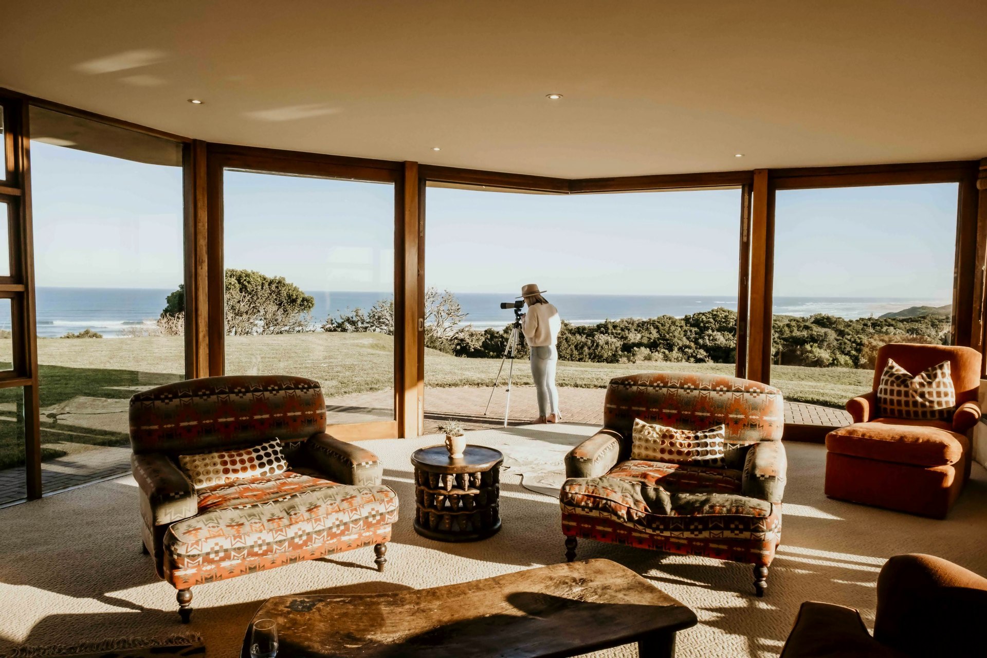 The lounge with wrap-around ocean views, oversized chairs and the outdoor deck beyond