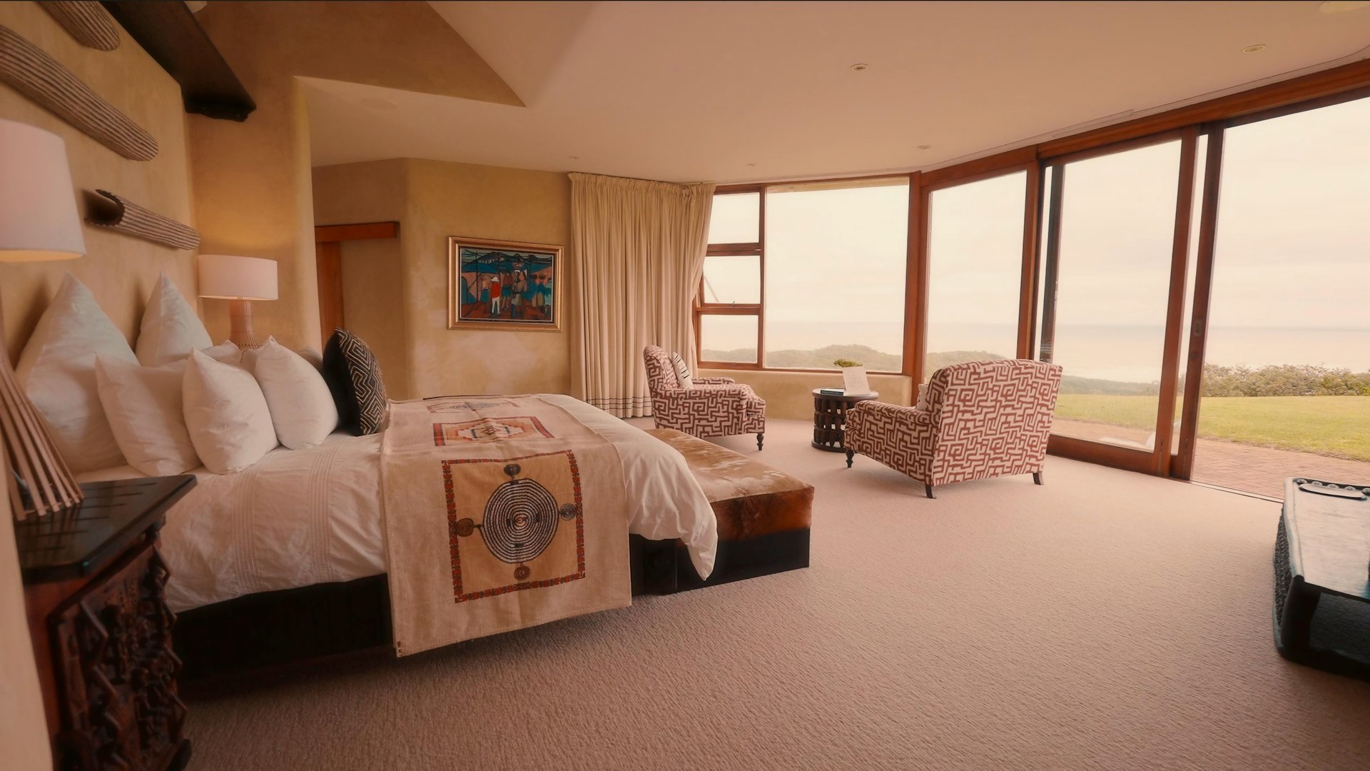 The primary bedroom, king bed facing the ocean beyond sheer curtains