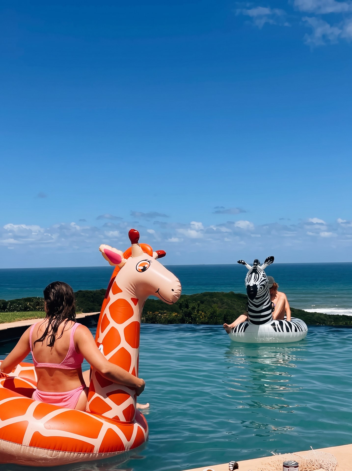 Guests floating in the infinity pool on oversized giraffe and zebra inflatables