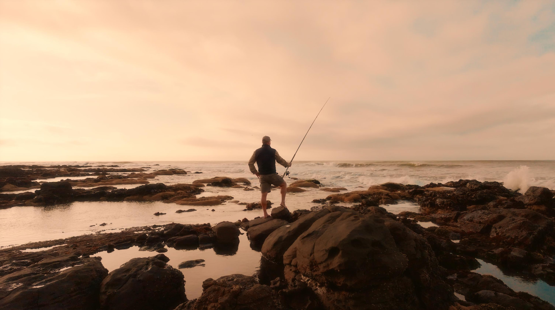 A guest rock fishing among tidal pools at dusk