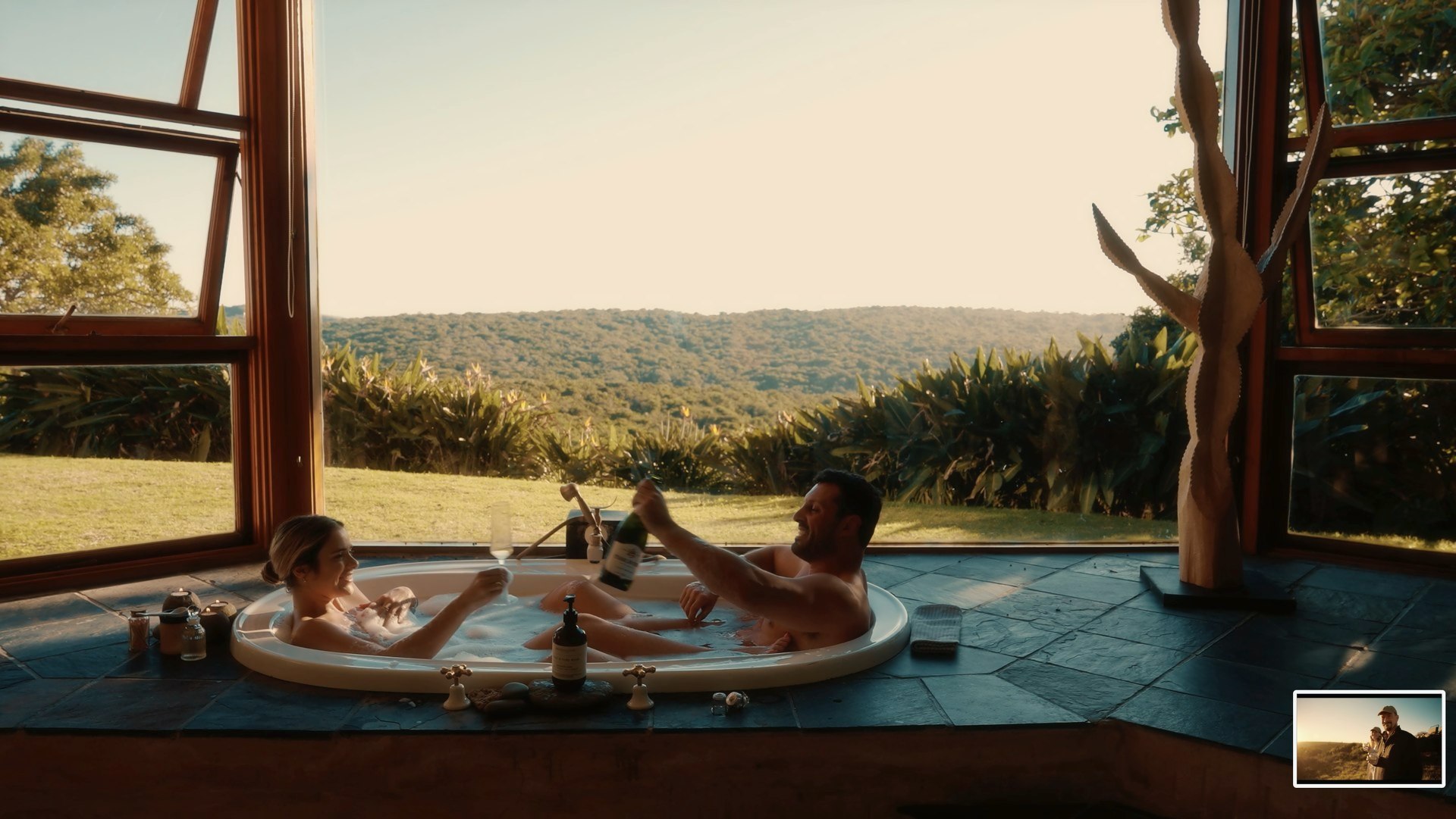 A couple toasting in the bathtub overlooking the reserve at Sandcastle Villa