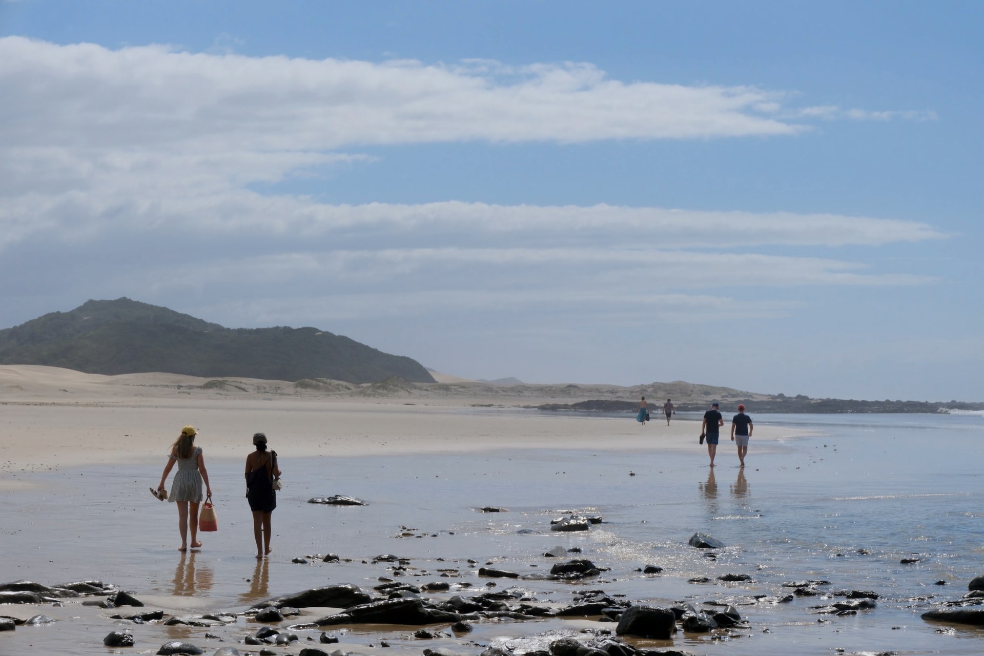 Two guests walking the wide tidal flats as the surf breaks behind them